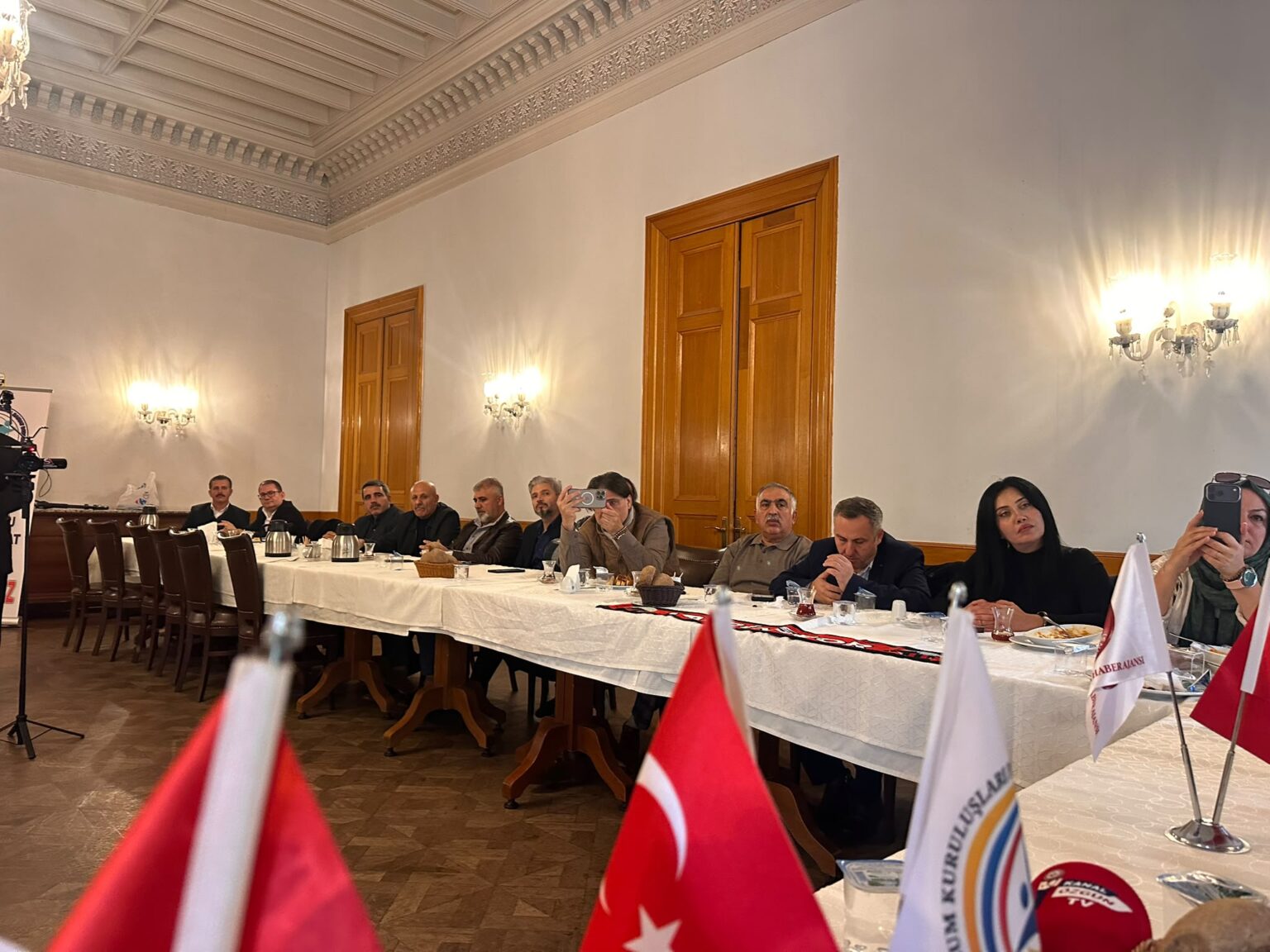 Dernek toplantısını izleyen katılımcılar ve masadaki Türk bayrakları